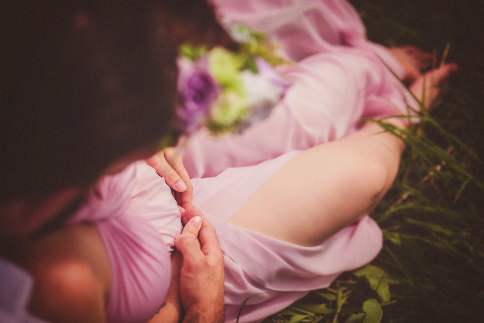 a woman in a pink dress laying on the ground