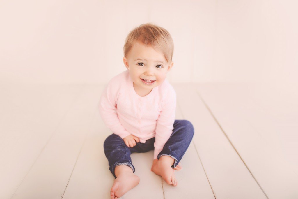 a smiling baby girl sitting on the floor
