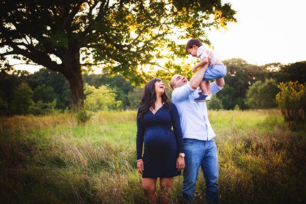 a man and woman holding a baby in a field