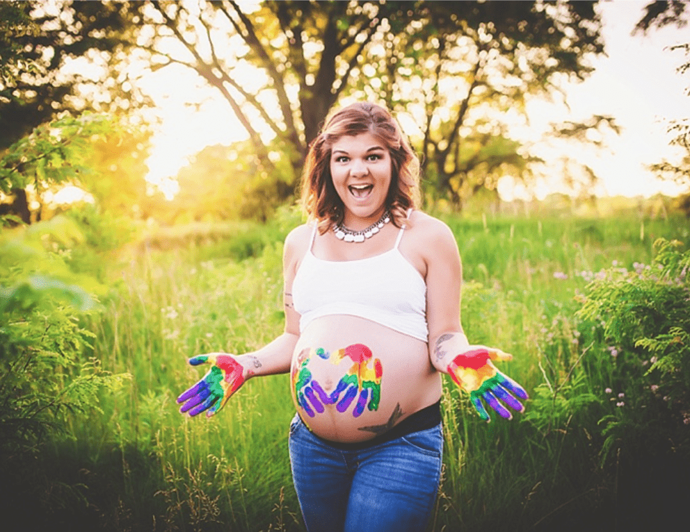 a pregnant woman with her hands painted in rainbow colors
