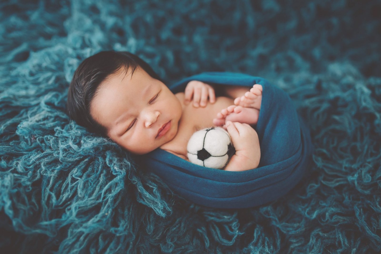 a baby is laying down with a soccer ball