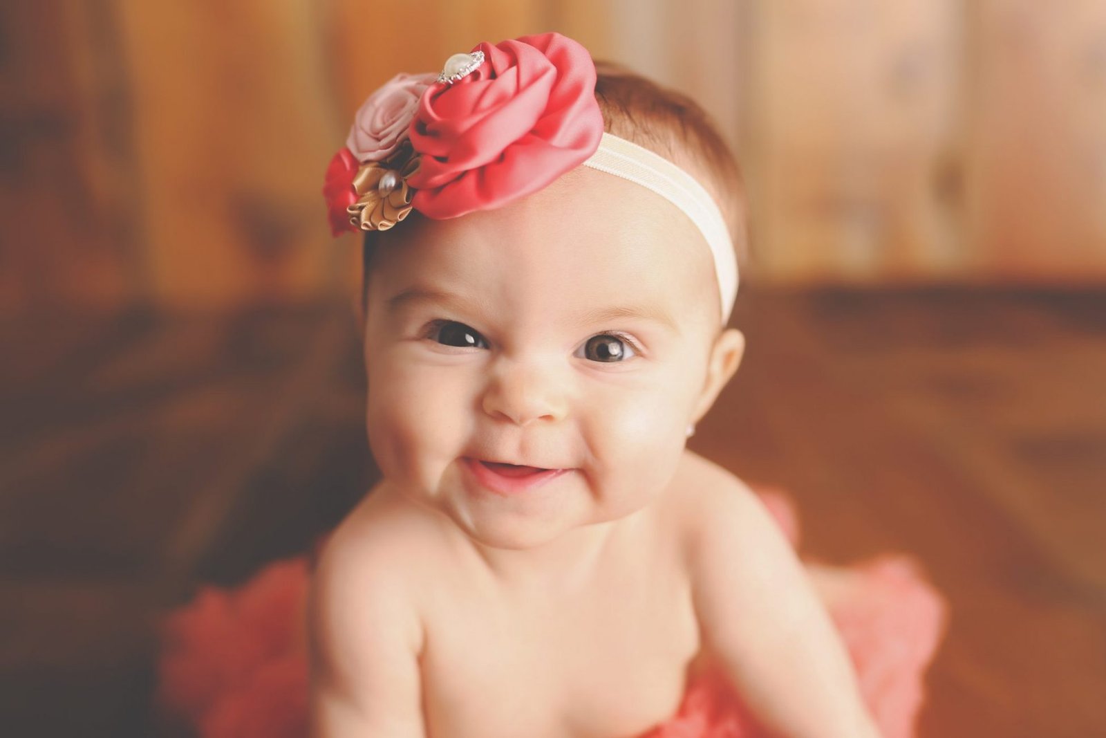 a baby girl wearing a pink dress and a flower in her hair