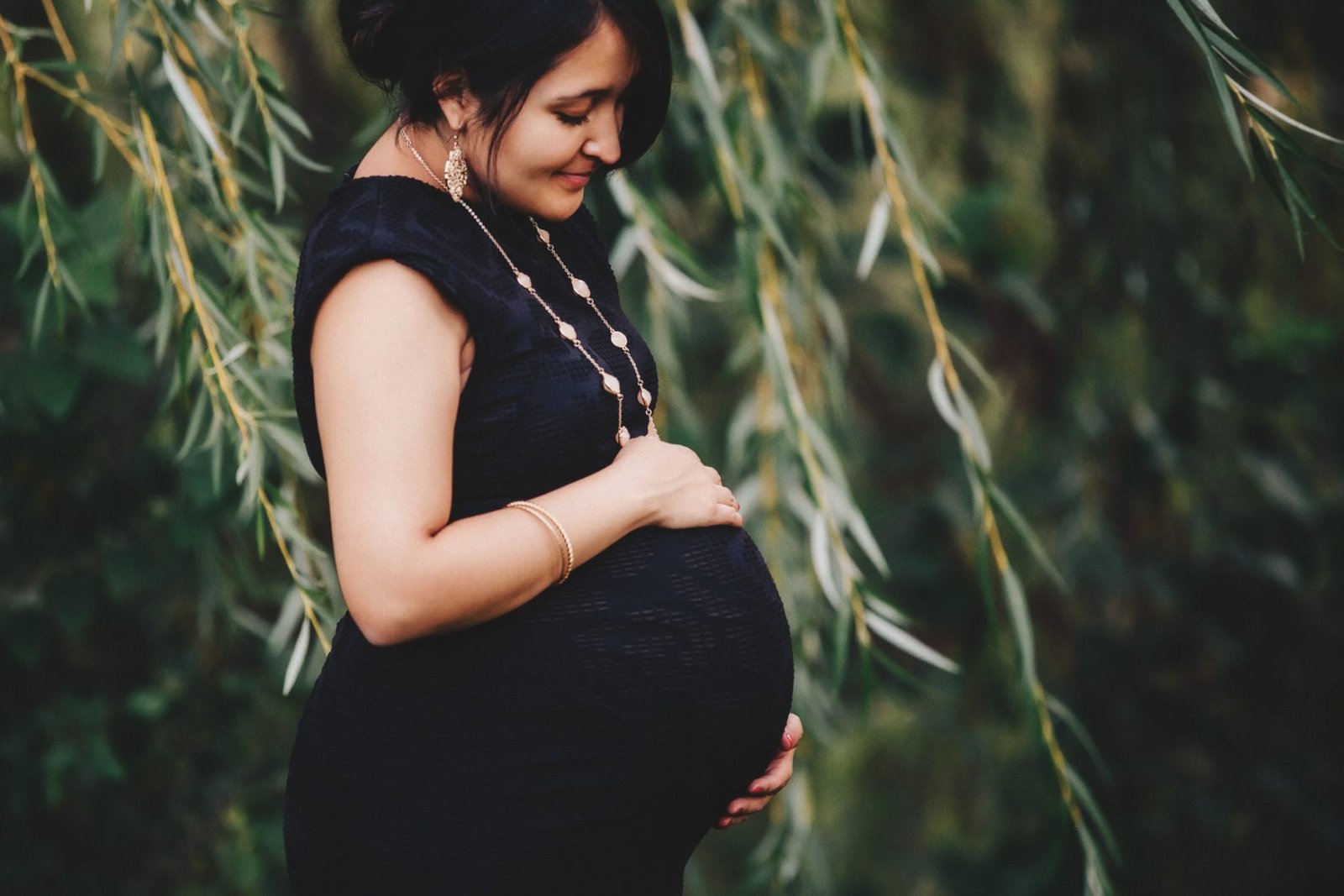 a pregnant woman standing in front of a tree