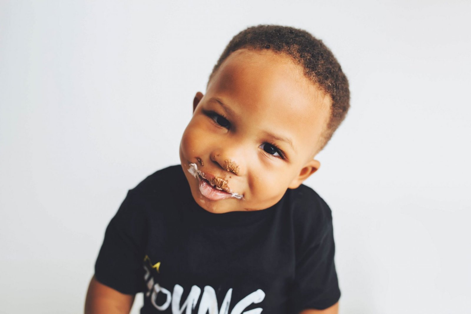 a young boy with a piece of food in his mouth
