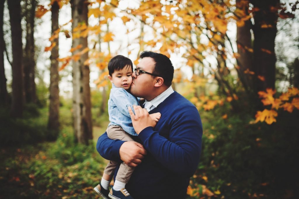 a father holding his son in the woods