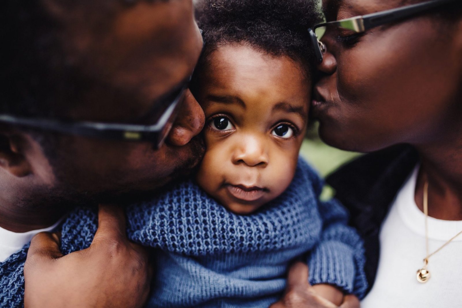 a woman and man kissing a small child