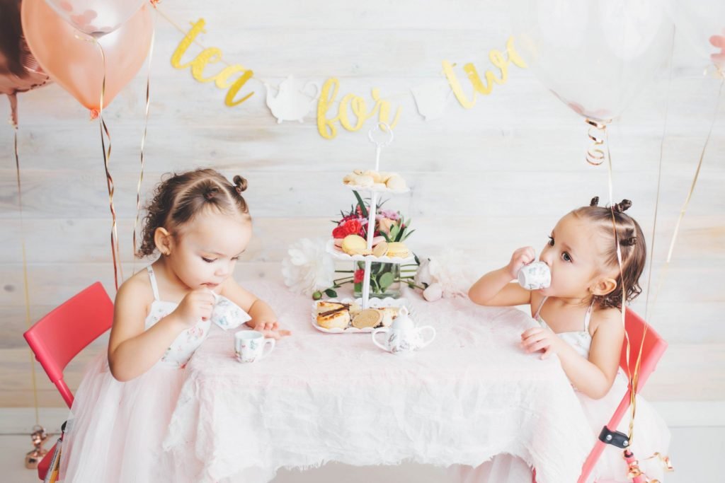 two little girls sitting at a table with tea cups