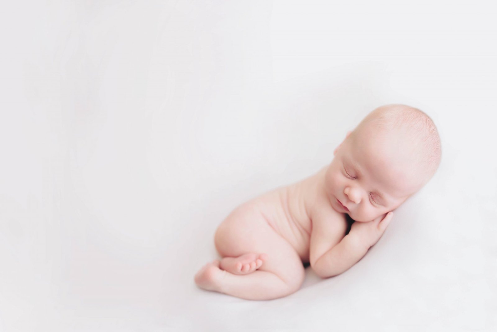 a baby is laying on its side with his head in his hands